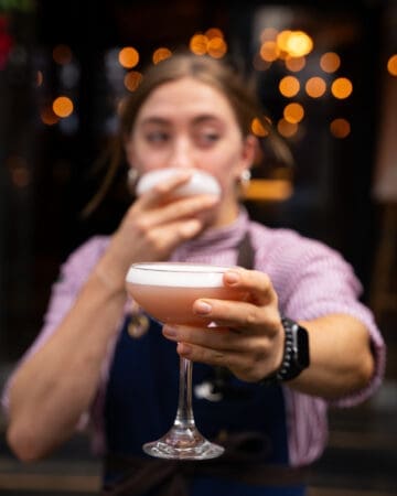 woman holding cocktails at restaurant entrance