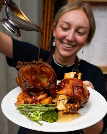 gravy being poured over roasted dish by waitress
