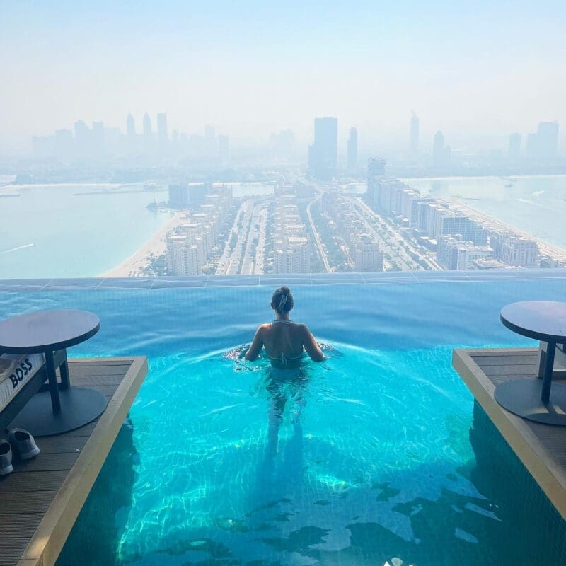 woman in infinity edge pool with city view of skyscrapers