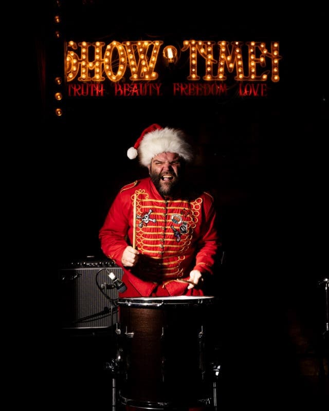 man dresses in red with santa red playing the drum
