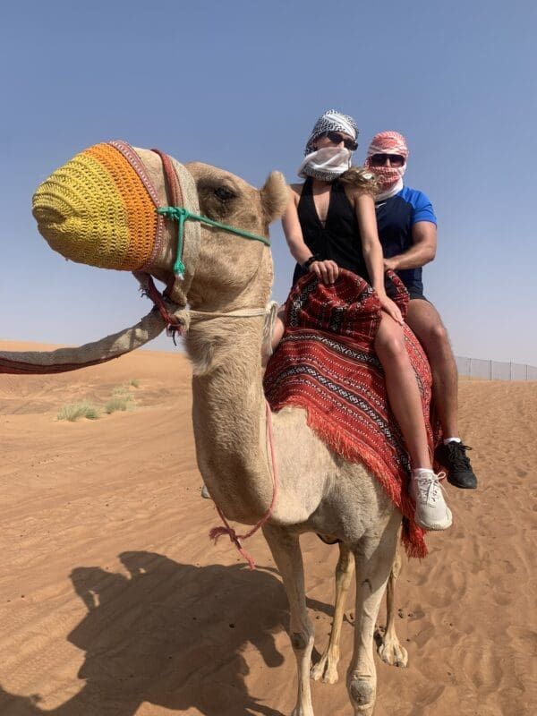 woman and man riding a camel in the desert