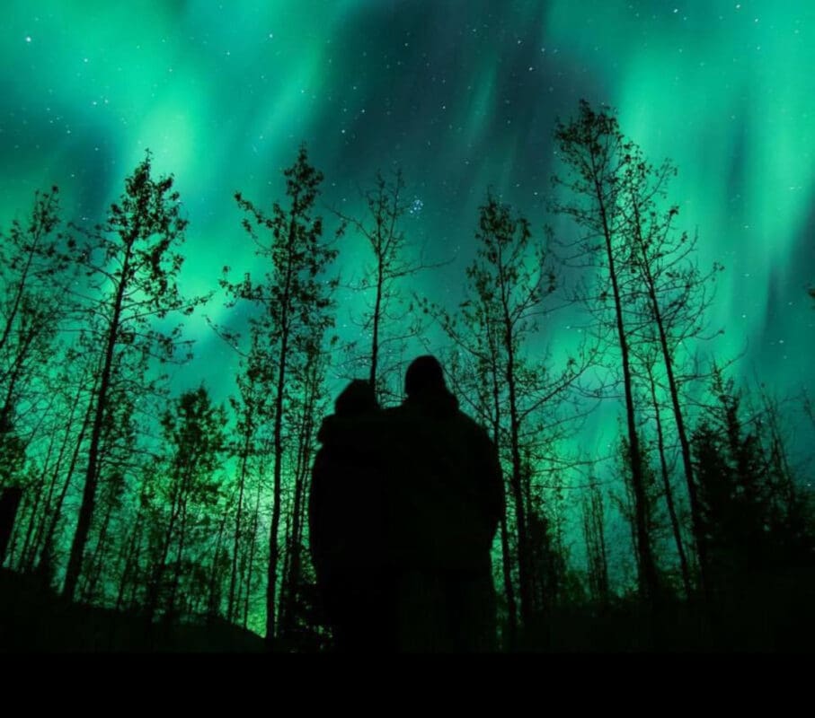 two people in the dark watching the northern lights