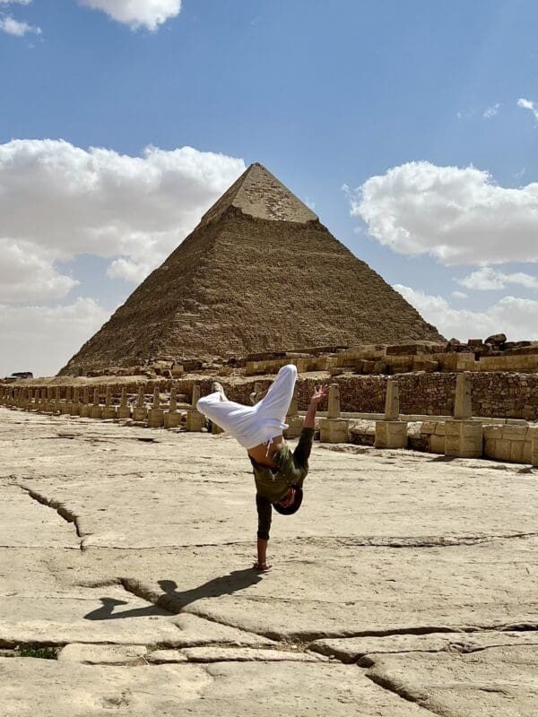 man doing handstand in front of pyramid