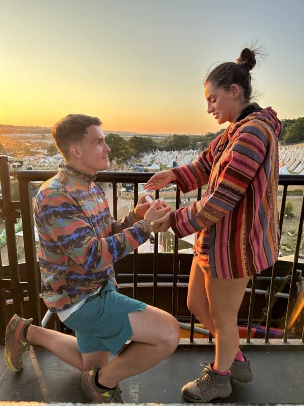 man on his knees proposing to woman with beautiful view behind