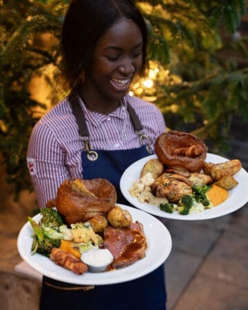 happy woman holding plates of sunday roast meals